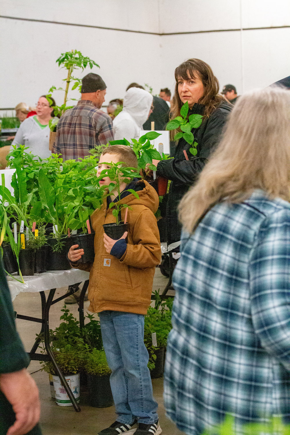 A young boy and his mother hold new plants at the Master Gardener Plant Sale at the Southwest Washington Fairgrounds.